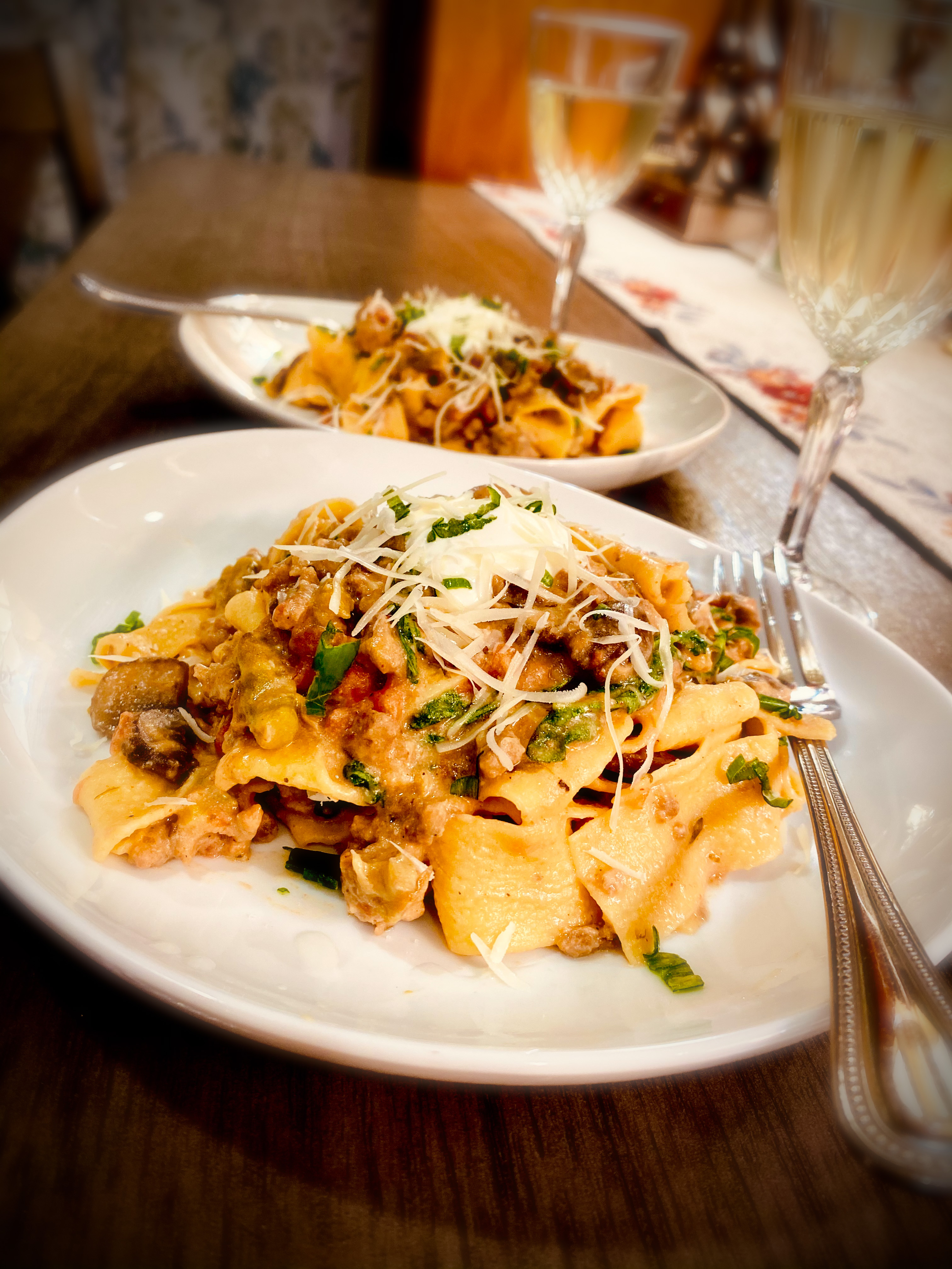 A creamy white bean and ricotta ragu bianco served over wide ribbons of pappardelle pasta, garnished with fresh herbs and a dollop of crème fraîche.