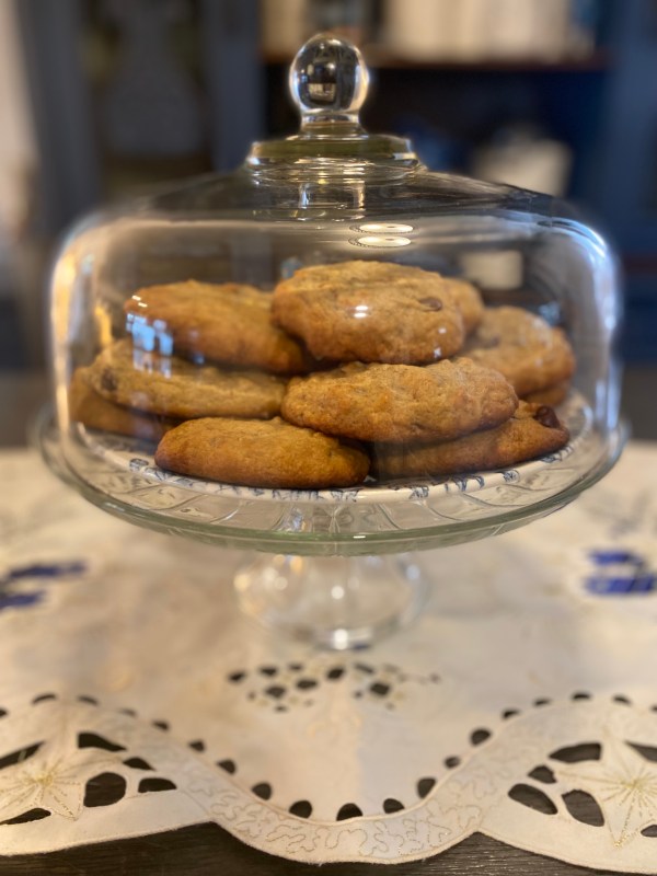 Photo of banana walnut cookies with chopped nuts and golden brown edges on a vintage plate.