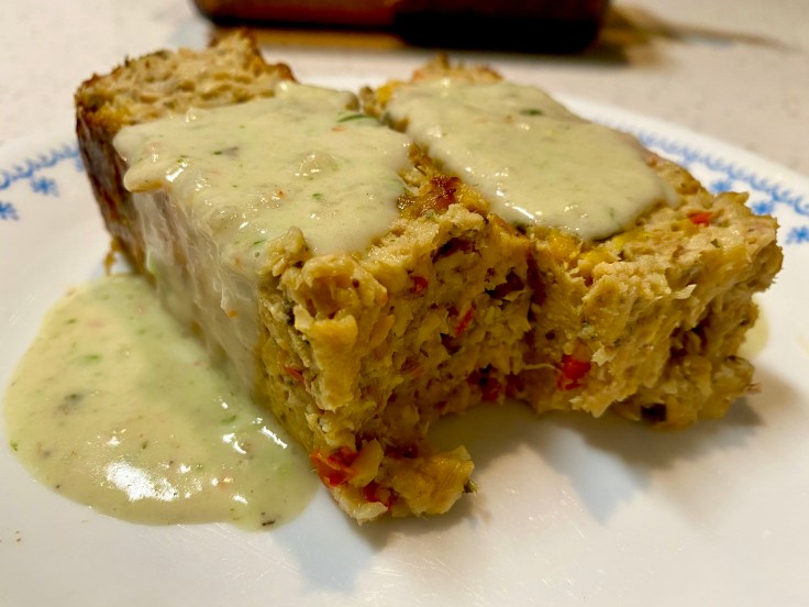 A retro-style salmon loaf topped with creamy shrimp sauce, served in a glass baking dish with vintage silverware and parsley garnish.