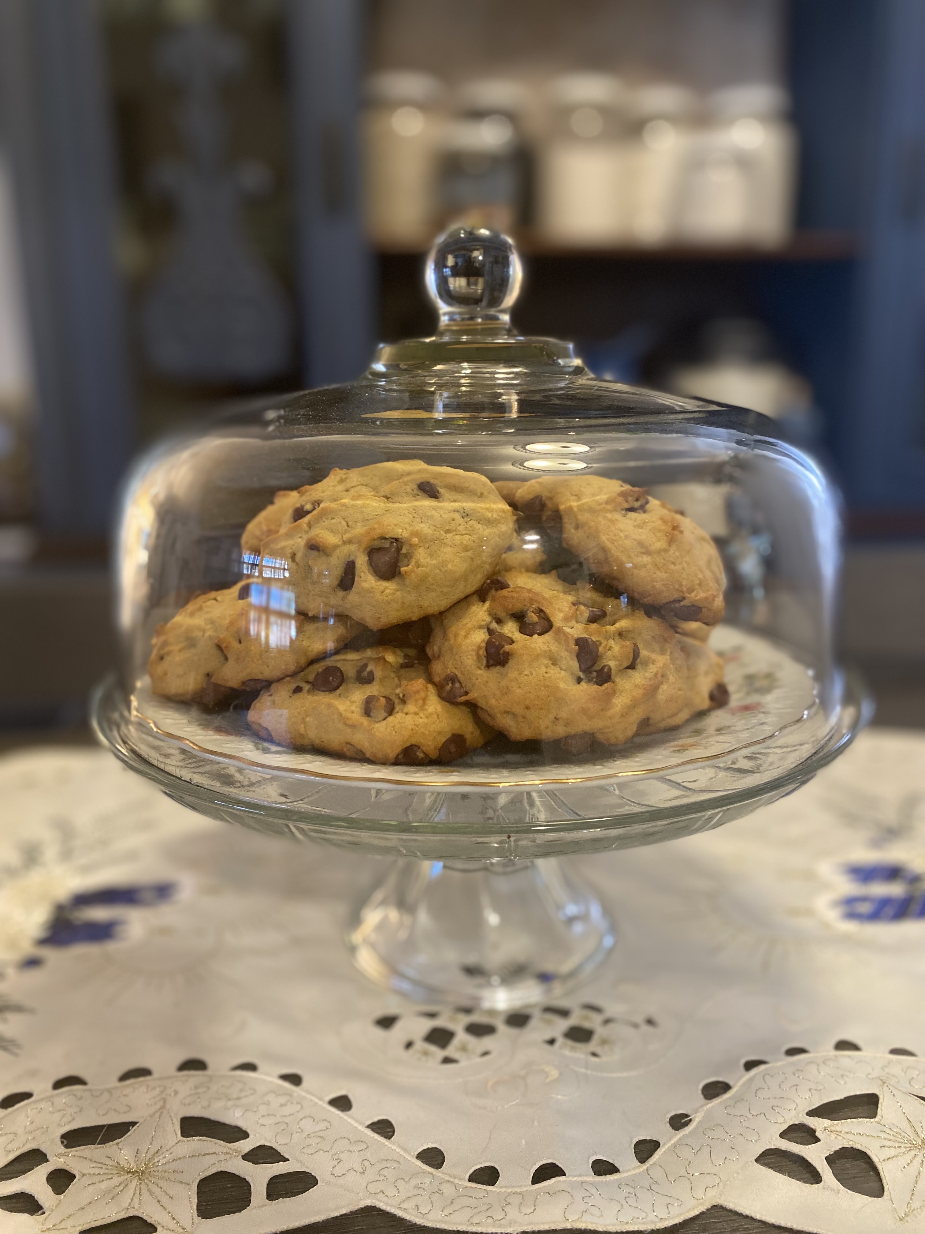 Soft pumpkin chocolate chip cookies with a fluffy, cake-like texture, stacked on a vintage plate beside a warm cup of tea.