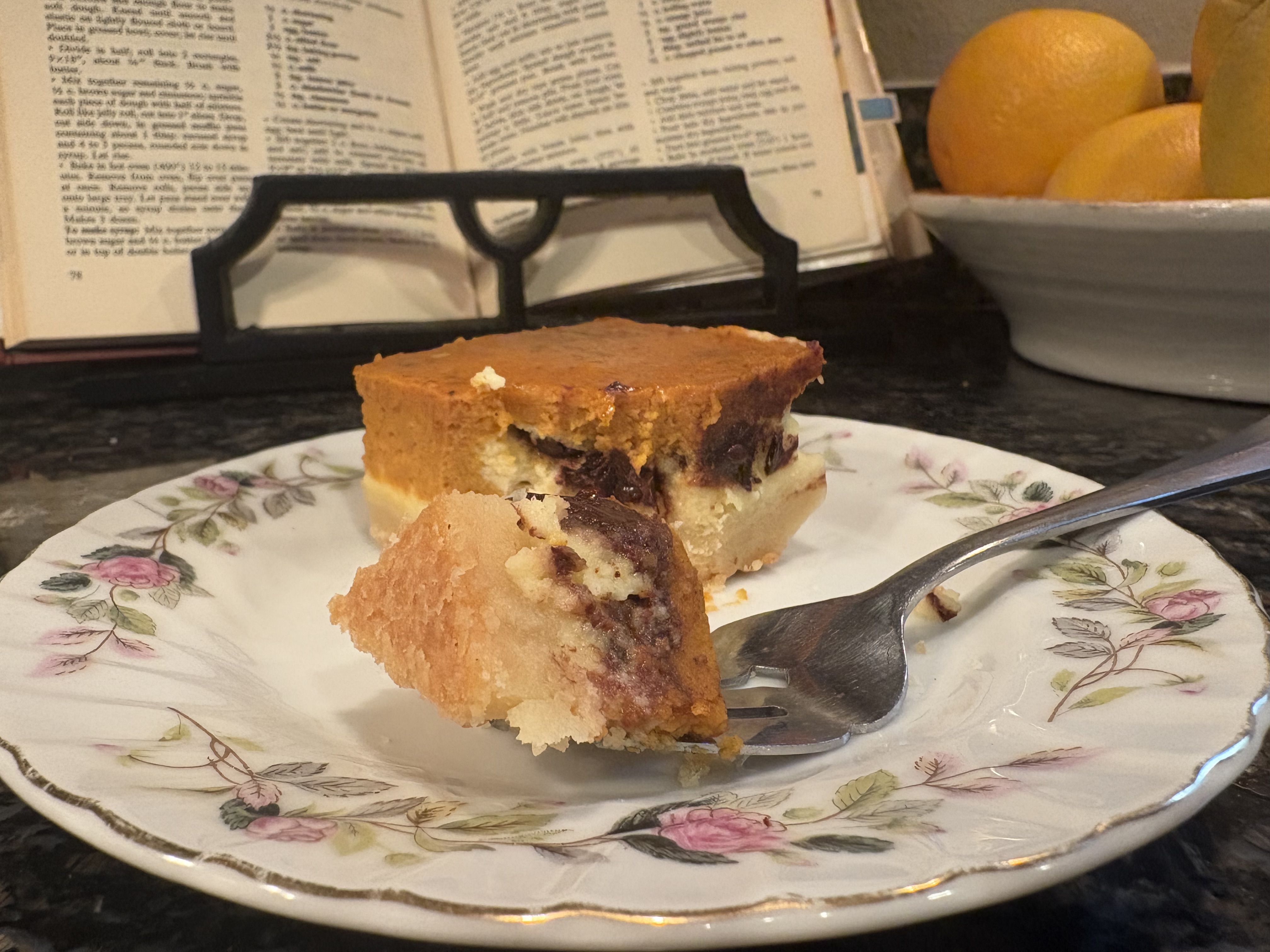 Pumpkin cheesecake chocolate chip bar on a vintage floral plate with an open cookbook in the background