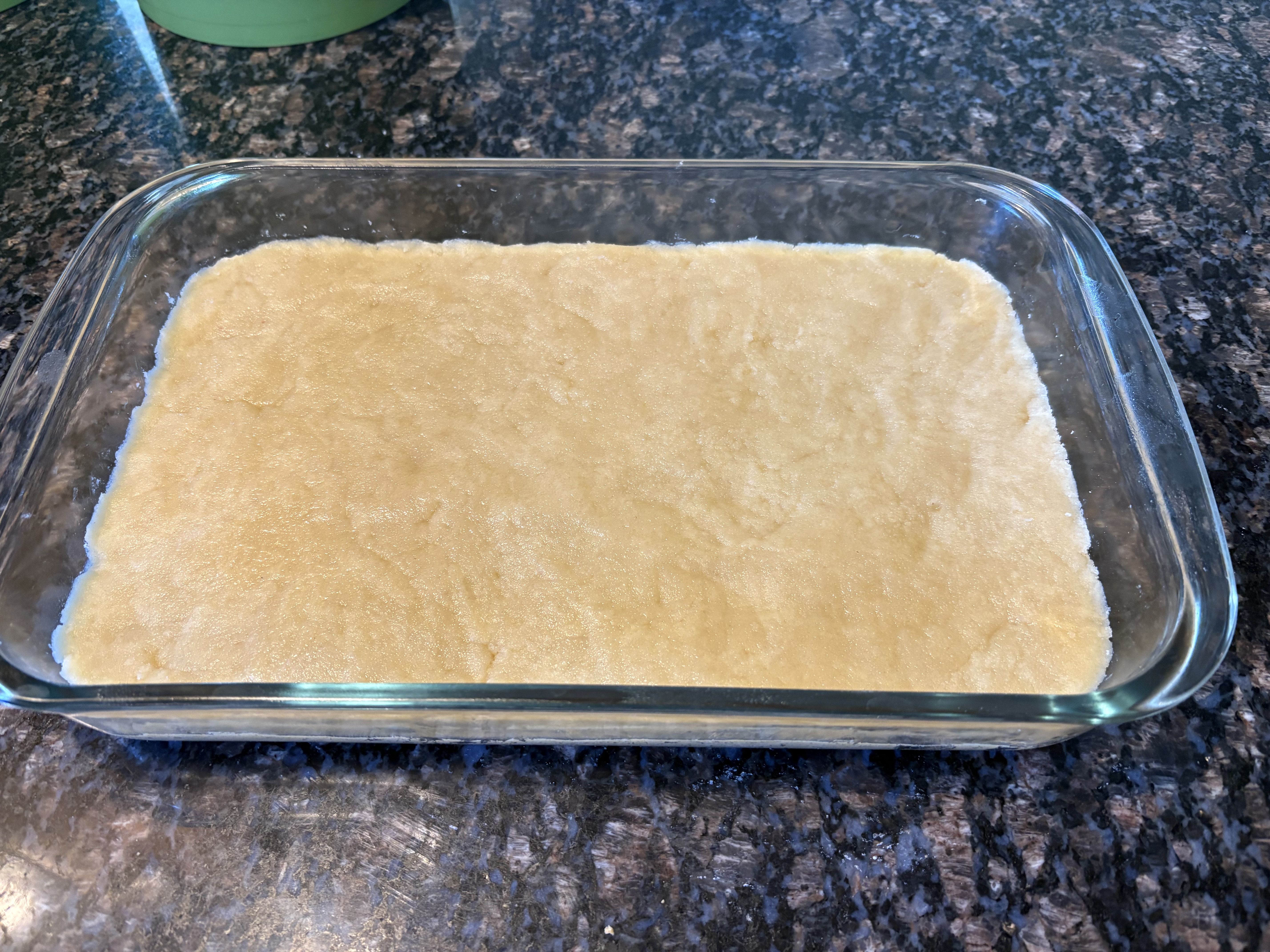 Shortbread crust pressed into a glass baking dish, ready for baking